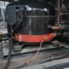 UL 3590 application Crankcase heater band clamped around the base of a refrigeration compressor with its silicone heating element lead running to the terminal box