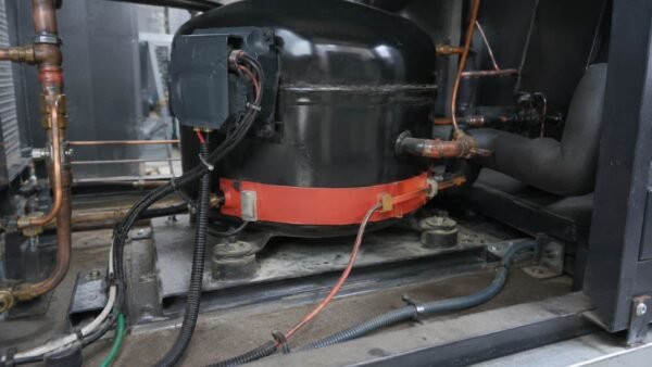 UL 3590 application Crankcase heater band clamped around the base of a refrigeration compressor with its silicone heating element lead running to the terminal box