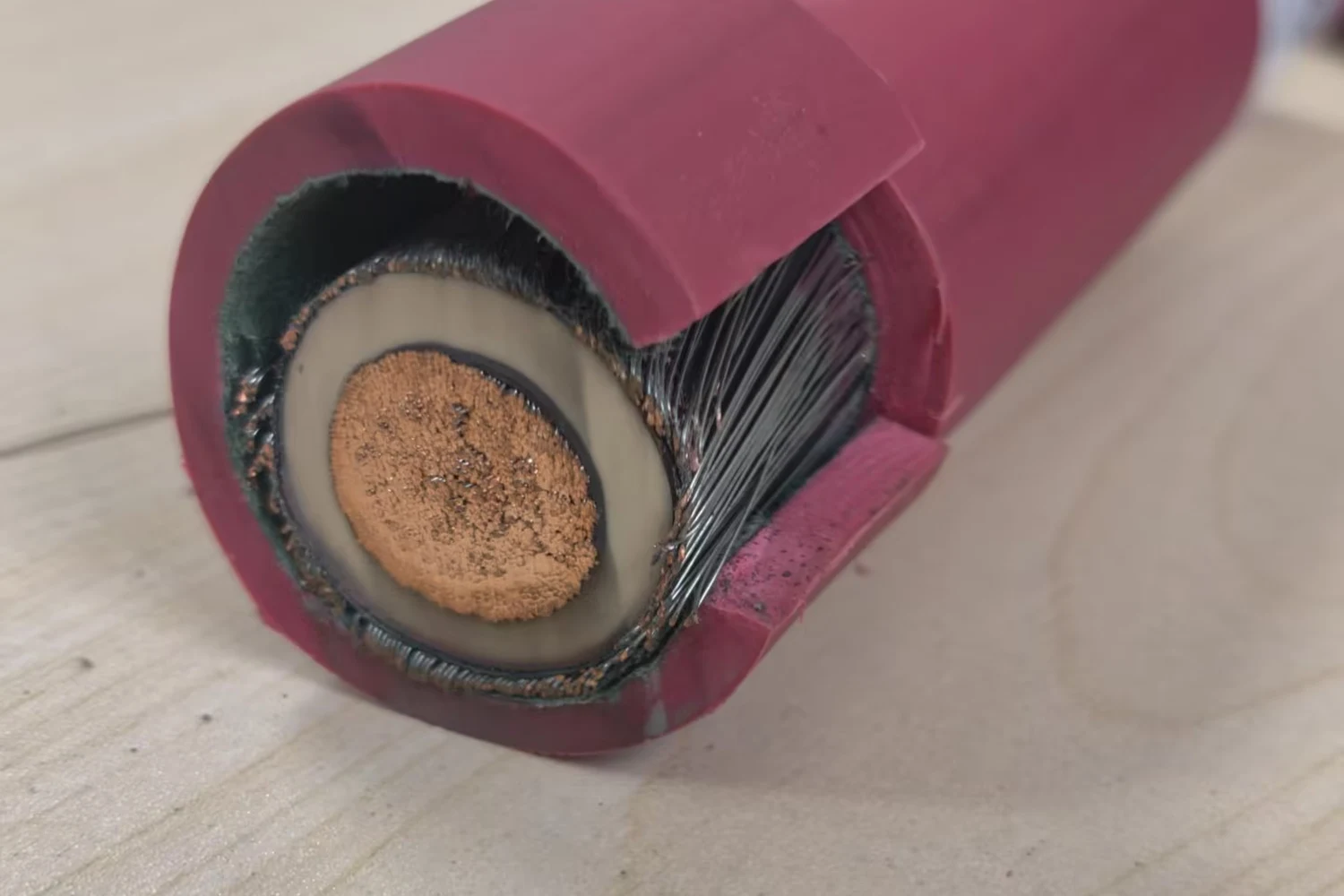 Tinned copper spiral wire shield exposed beneath a red cable jacket on a single-core cable sample