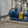 Black screened VFD motor cable linking an industrial pump motor and a closed drive cabinet