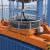 Black control cable entering a gravity-fed collector basket mounted on a container-crane spreader