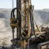 Карьерный вращательный буровой станок для взрывных скважин с черным круглым силовым и контрольным кабелем буровой мачты, проложенным в поддерживаемой подвижной петле вдоль вертикальной мачты