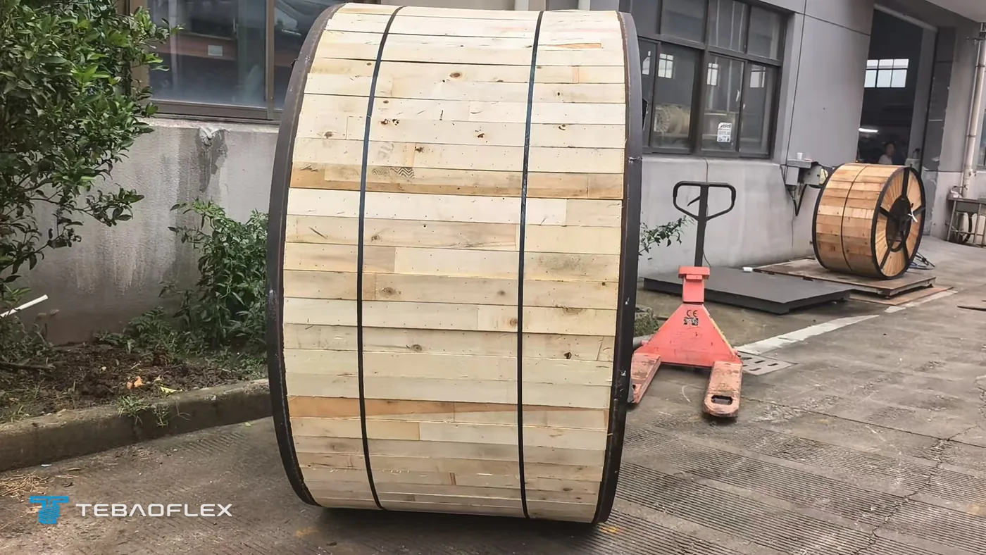 Cable drum closed with wooden lagging boards and steel straps, waiting beside a pallet truck before loading