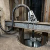 Cabo armado autoportante de descida para furos de sonda e poços de mina (0.6/1–15 kV) — cenário de aplicação Boca do cavalete do poço de mina e entrada do furo de sonda onde um cabo alimentador preto armado de serviço pesado é ancorado num grampo de suspensão de aço