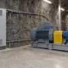 Чёрный шахтный кабель VFD на опорах между закрытым шкафом преобразователя и закрытой клеммной коробкой двигателя на шахтной насосной станции
