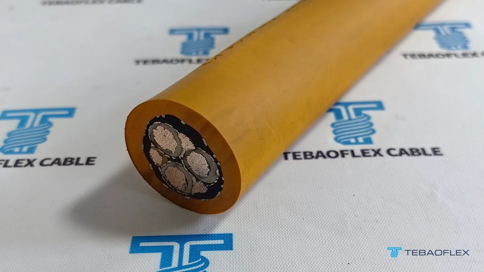 Extrémité coupée du câble minier blindé TEBAOFLEX SHD-GC 2 kV 3×6+2×10+1×10 AWG à gaine en TPU orange, sur un tissu TEBAOFLEX CABLE